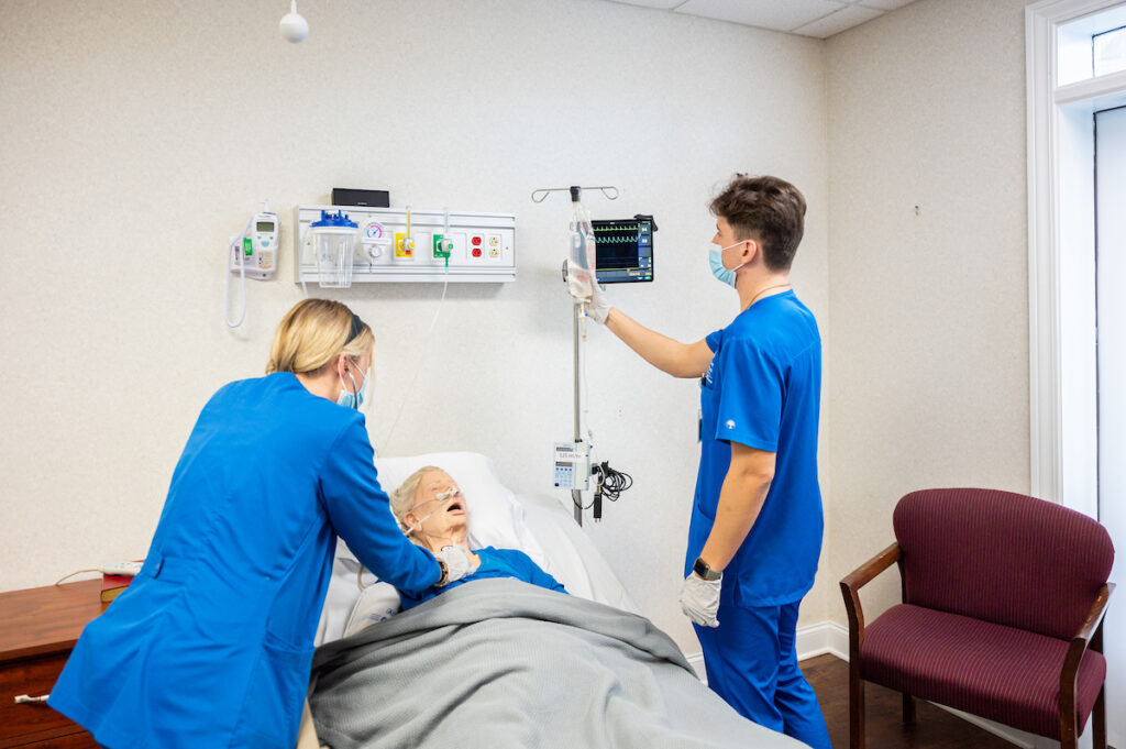 two nursing students studying on a dummy