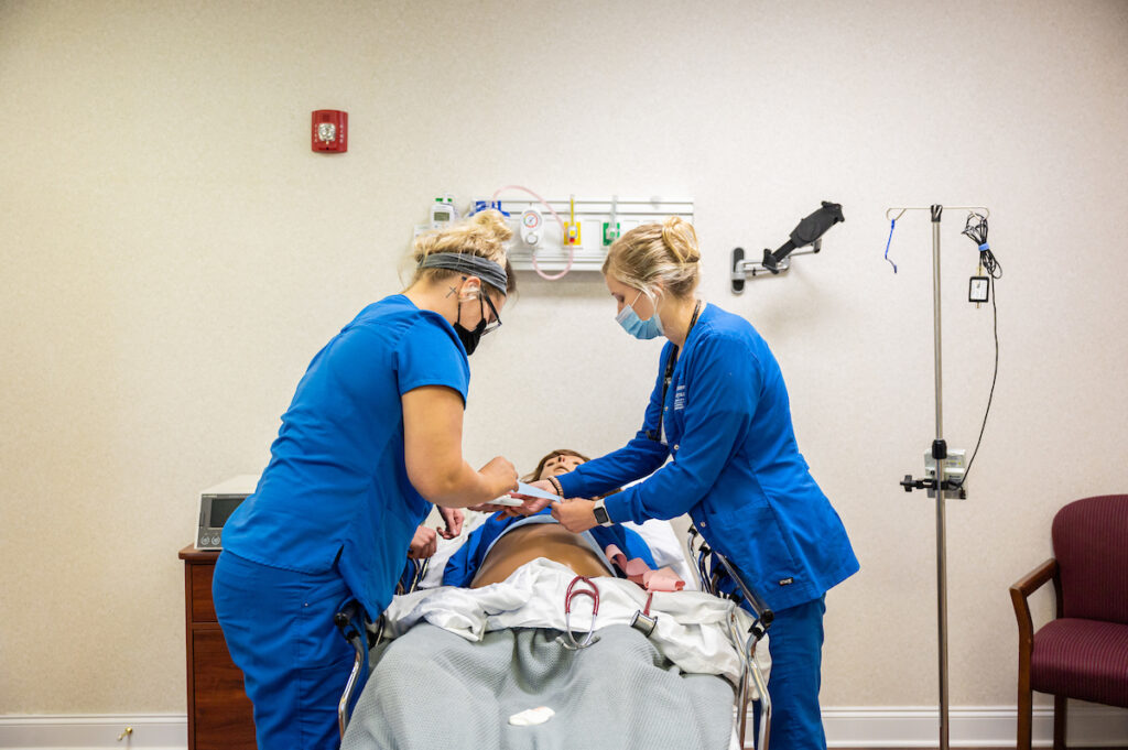 two nursing students studying on a dummy