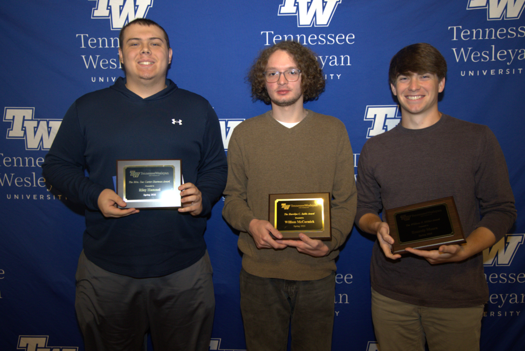 Three men stand side by side, each holding a plaque at a Tennessee Wesleyan University event, posing for a photo in front of a blue backdrop with logos.