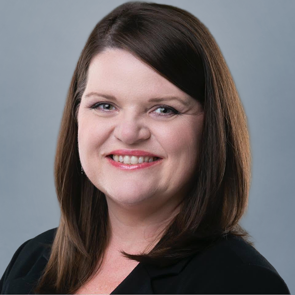 Professional headshot of a smiling woman with shoulder-length brown hair against a gray background, wearing a black blazer.