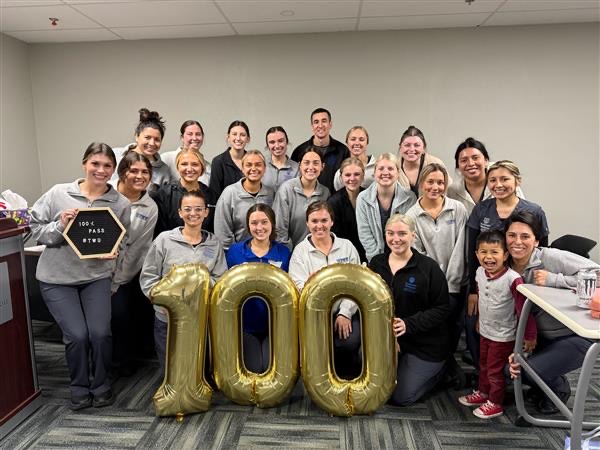 Dental hygiene students pose with balloons that make a "100"