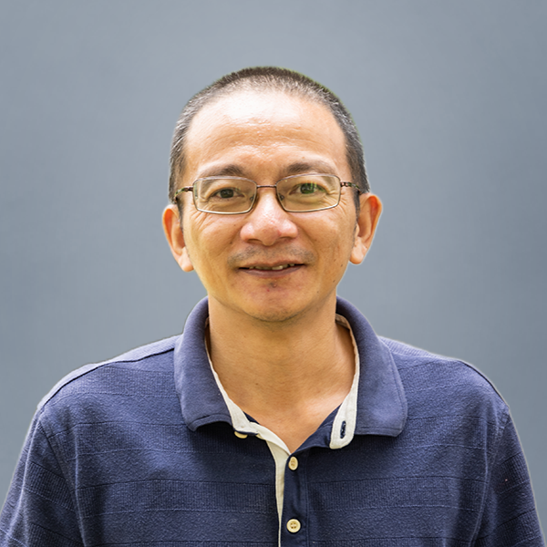 Portrait of a man wearing glasses and a navy polo shirt, smiling at the camera.