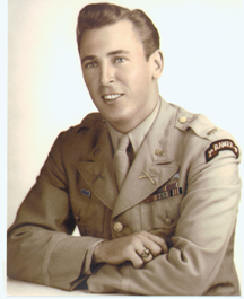 2LT_Leonard_Lomell | Tennessee Wesleyan University Portrait of a young man in a WWII-era military uniform, seated with arms folded on a table and smiling.