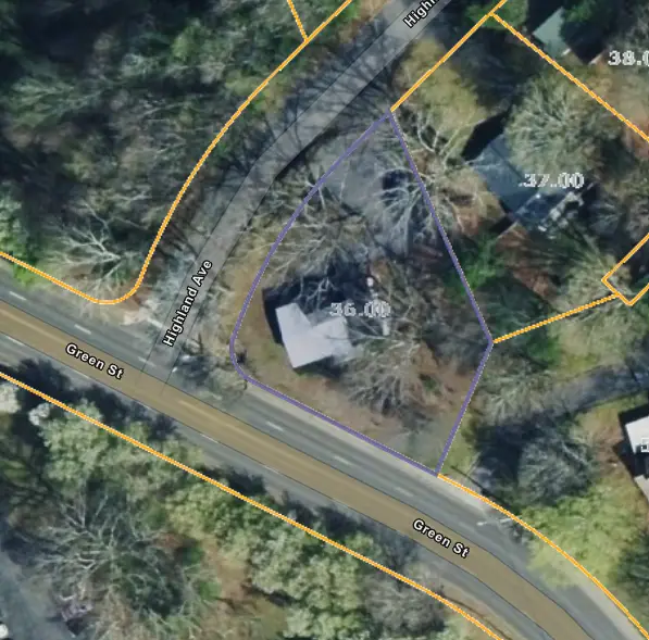 Aerial view of a property at the corner of Green St and Highlands Ave, outlined in purple within orange parcel lines, with a house among trees.