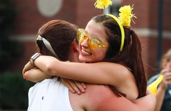 friends embracing in front of commons dormitory